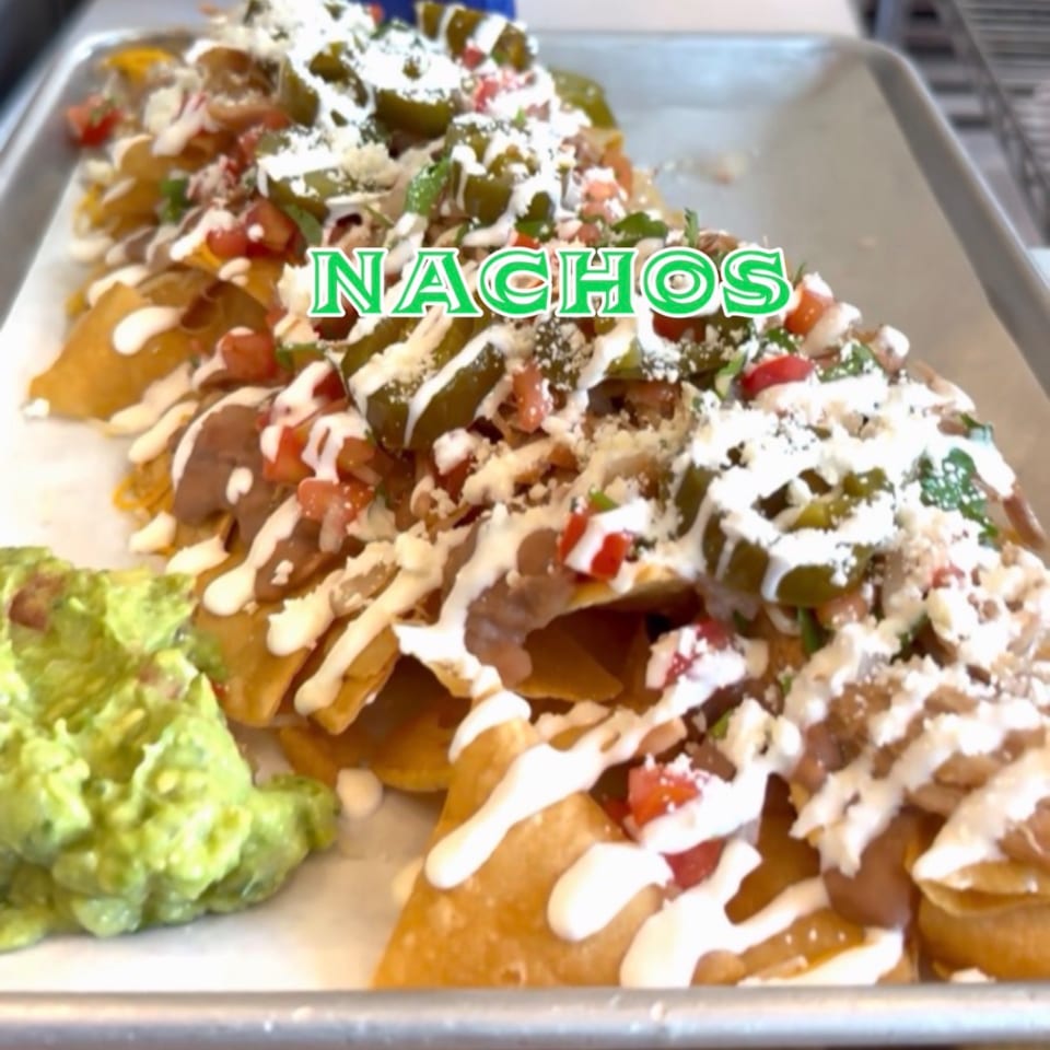 A tray of Taco el Diablo's nachos with refried beans, jalapeños, pico de gallo, and a side of guacamole.