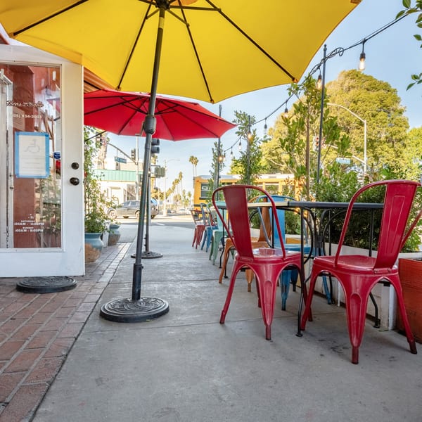 Taco el Diablo's vibrant outdoor patio with red and yellow umbrellas, colorful chairs, and string lights.