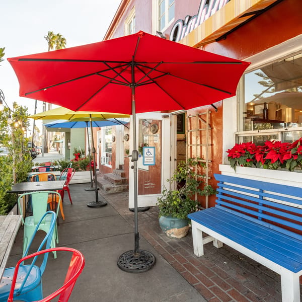 Colorful outdoor seating with red, yellow, and blue umbrellas, and vibrant chairs outside Taco el Diablo.
